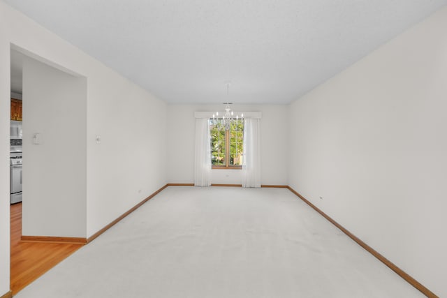 unfurnished room featuring an inviting chandelier and hardwood / wood-style floors