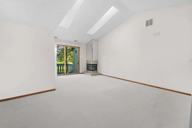 unfurnished living room featuring a textured ceiling, lofted ceiling with skylight, and light carpet