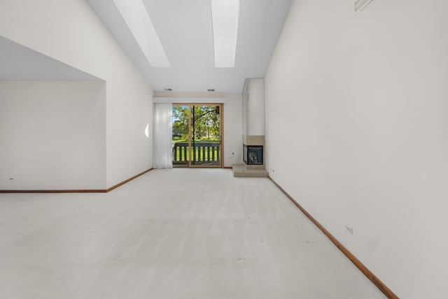 unfurnished living room with light carpet, a fireplace, and lofted ceiling with skylight