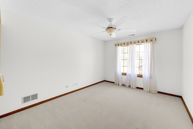 spare room featuring ceiling fan, light colored carpet, and a textured ceiling