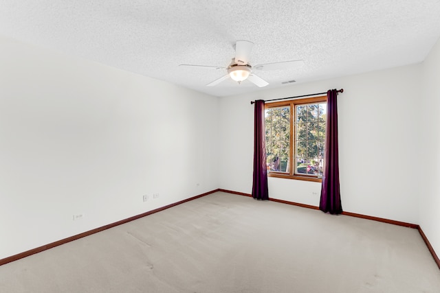 unfurnished room with a textured ceiling, ceiling fan, and light carpet