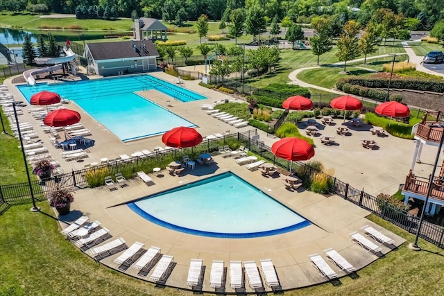 view of pool featuring a water view, a water slide, a patio area, and a lawn