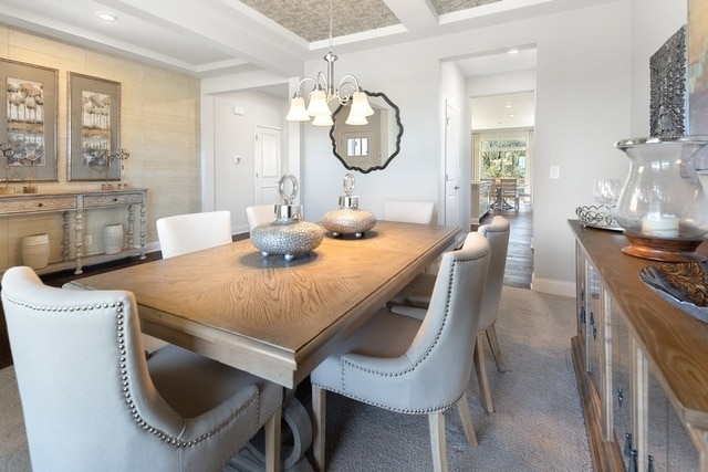 dining area featuring dark carpet, a chandelier, and beamed ceiling