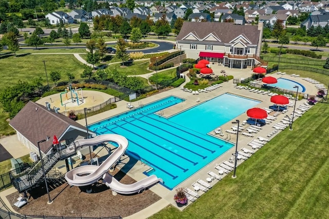 view of swimming pool featuring a lawn, a water slide, and a patio area