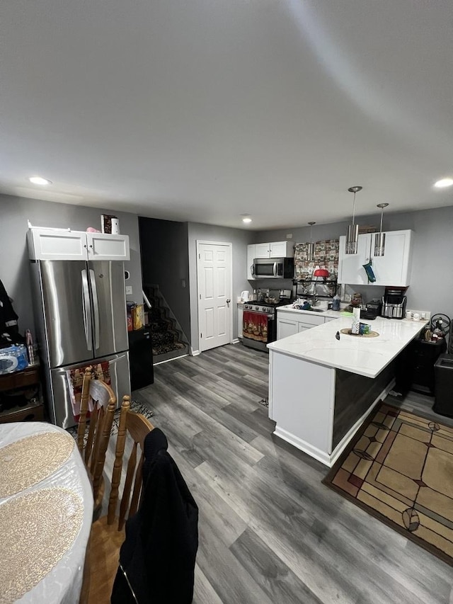 kitchen with white cabinetry, appliances with stainless steel finishes, decorative light fixtures, and kitchen peninsula