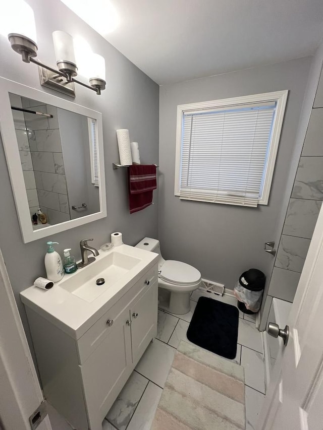 bathroom featuring vanity, a tile shower, and toilet