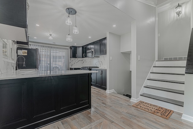 kitchen with pendant lighting, tasteful backsplash, appliances with stainless steel finishes, crown molding, and light hardwood / wood-style floors