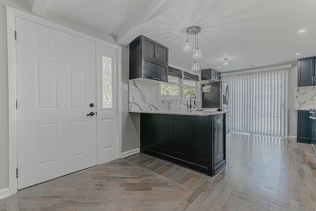 kitchen with light wood-type flooring, decorative backsplash, sink, and hanging light fixtures