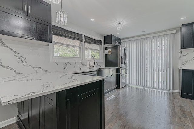 kitchen featuring pendant lighting, wood-type flooring, backsplash, and stainless steel refrigerator with ice dispenser