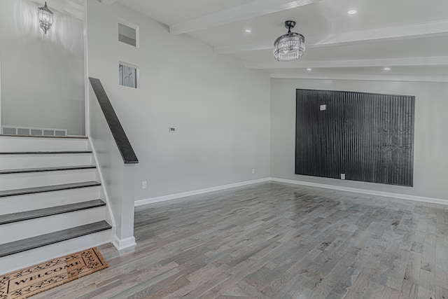 empty room featuring beam ceiling and light hardwood / wood-style floors