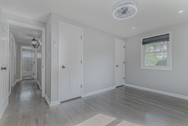 unfurnished bedroom with a notable chandelier and light hardwood / wood-style flooring