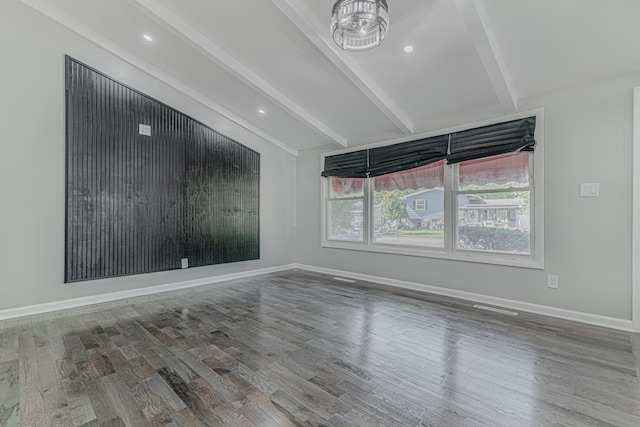 empty room featuring vaulted ceiling with beams and wood-type flooring