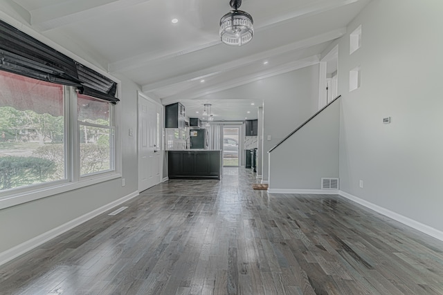 unfurnished living room with lofted ceiling with beams, a healthy amount of sunlight, and dark hardwood / wood-style flooring