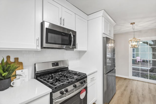 kitchen with pendant lighting, appliances with stainless steel finishes, tasteful backsplash, light hardwood / wood-style floors, and white cabinets