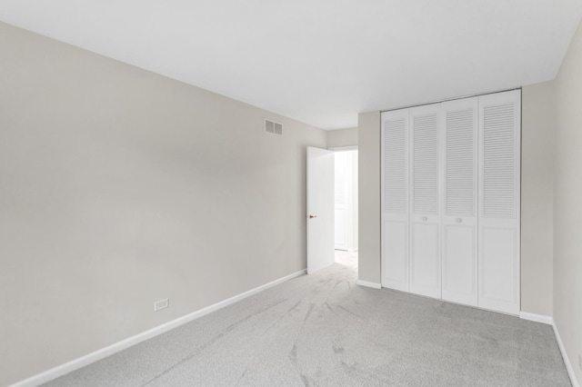 unfurnished bedroom featuring a closet and light carpet