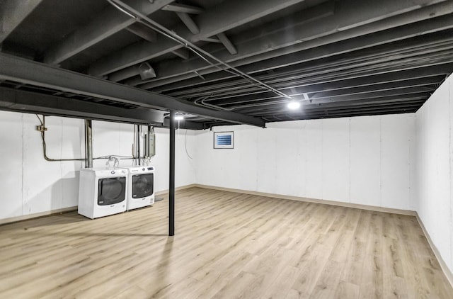 basement with electric panel, light hardwood / wood-style floors, and washer and dryer