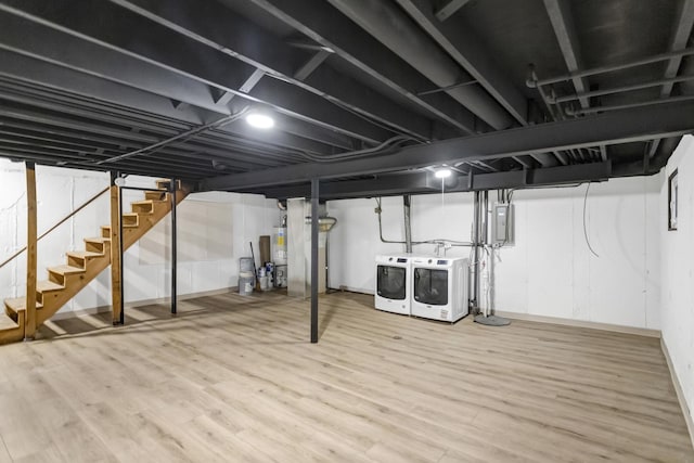 basement with water heater, hardwood / wood-style floors, electric panel, and independent washer and dryer