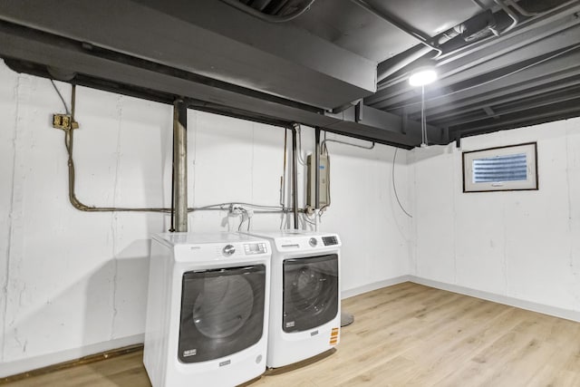 clothes washing area featuring washing machine and dryer and light hardwood / wood-style flooring