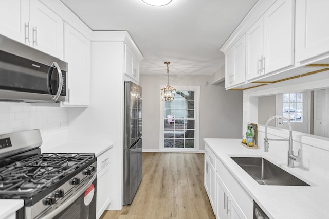 kitchen with stainless steel appliances, sink, white cabinets, and decorative backsplash