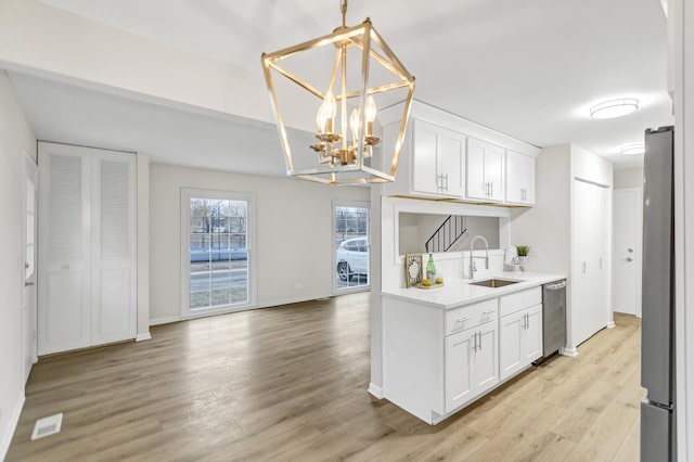 kitchen with sink, pendant lighting, stainless steel appliances, light hardwood / wood-style floors, and white cabinets