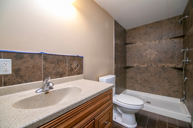 bathroom with vanity, tiled shower, and toilet