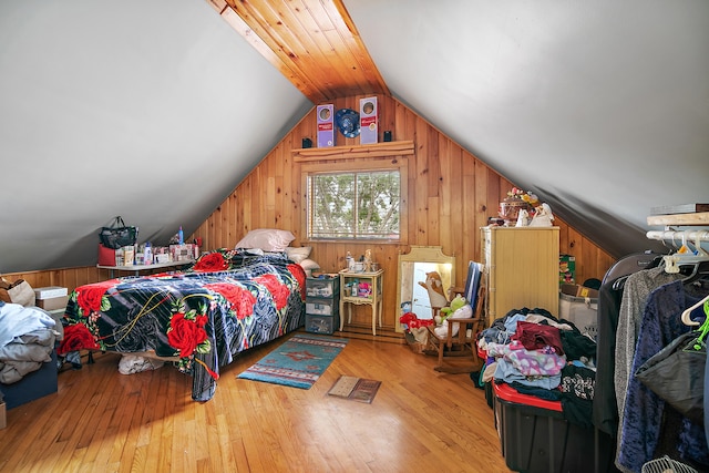 bedroom with lofted ceiling, wood walls, and light hardwood / wood-style flooring