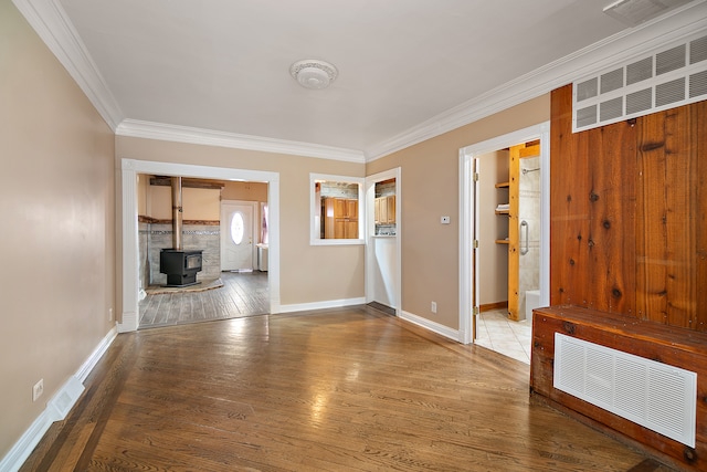 unfurnished living room with a wood stove, hardwood / wood-style floors, and ornamental molding