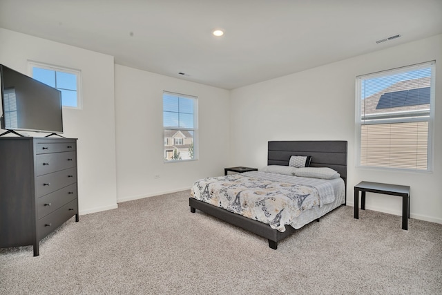 bedroom with multiple windows and light colored carpet