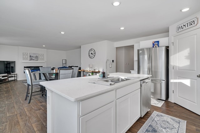 kitchen featuring dark hardwood / wood-style floors, sink, an island with sink, white cabinets, and stainless steel appliances