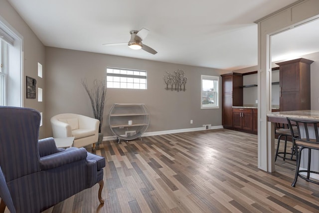 living area with visible vents, ceiling fan, light wood finished floors, and baseboards
