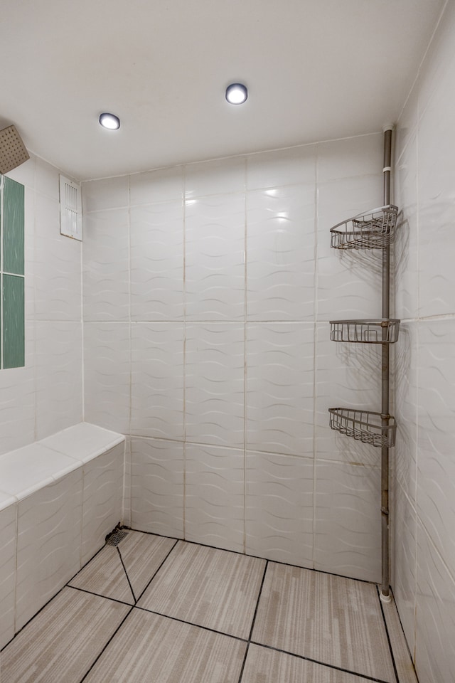 bathroom with a tile shower and tile walls