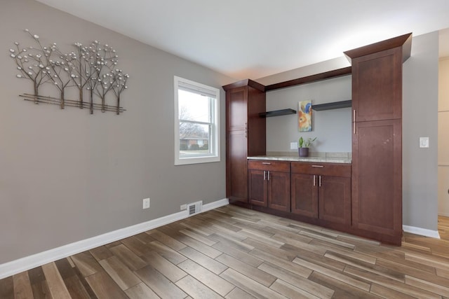 bar with visible vents, baseboards, and light wood finished floors