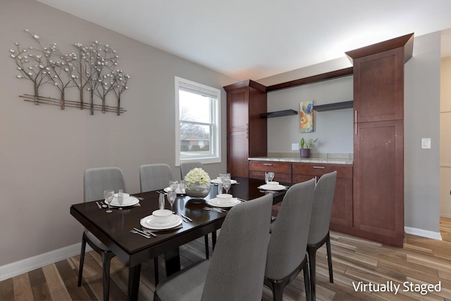 dining area featuring light wood finished floors and baseboards