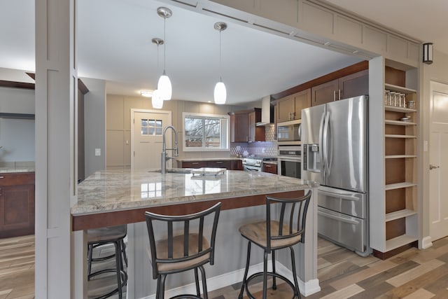 kitchen with wood-type flooring, appliances with stainless steel finishes, light stone counters, and sink