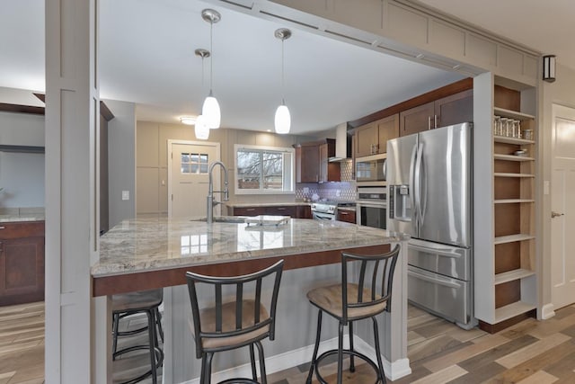 kitchen featuring backsplash, light wood-style floors, wall chimney exhaust hood, stainless steel appliances, and a sink