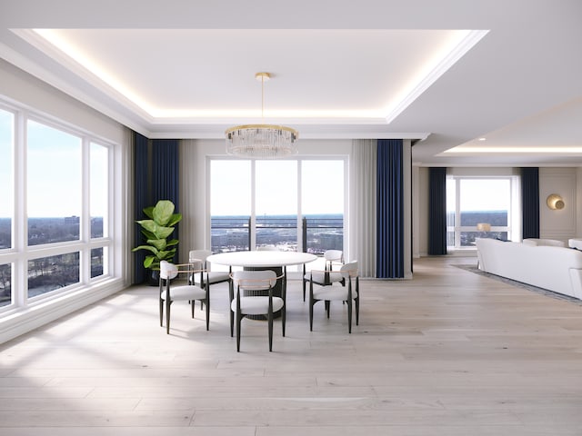 dining area with light wood-type flooring, a raised ceiling, an inviting chandelier, and plenty of natural light