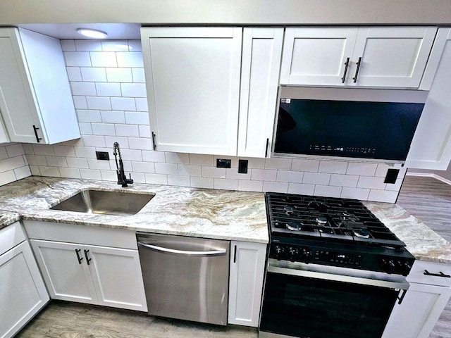 kitchen with stainless steel appliances, white cabinetry, and light hardwood / wood-style flooring