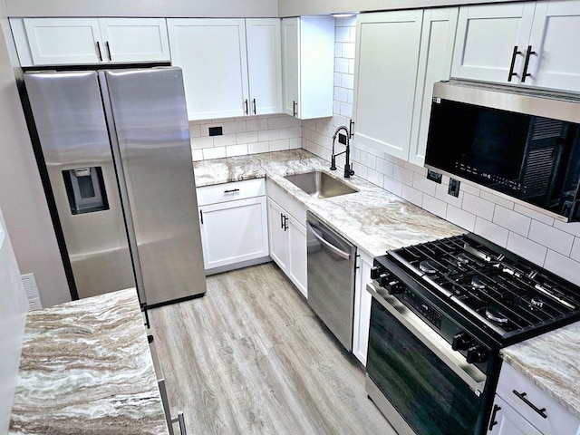 kitchen with decorative backsplash, stainless steel appliances, white cabinets, and light stone counters