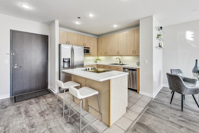 kitchen featuring sink, a kitchen island, stainless steel appliances, a kitchen breakfast bar, and light wood-type flooring