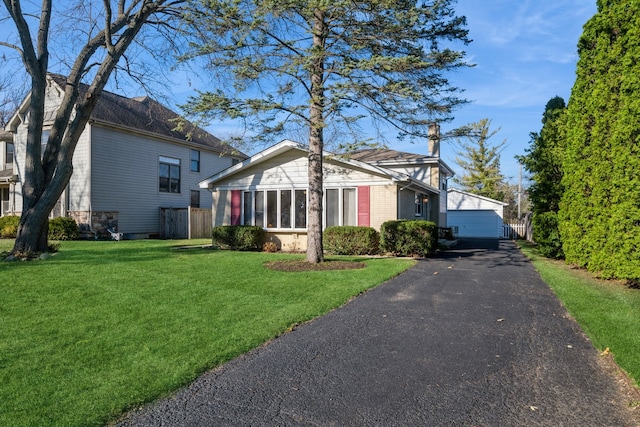 view of front facade with a garage, an outbuilding, and a front lawn