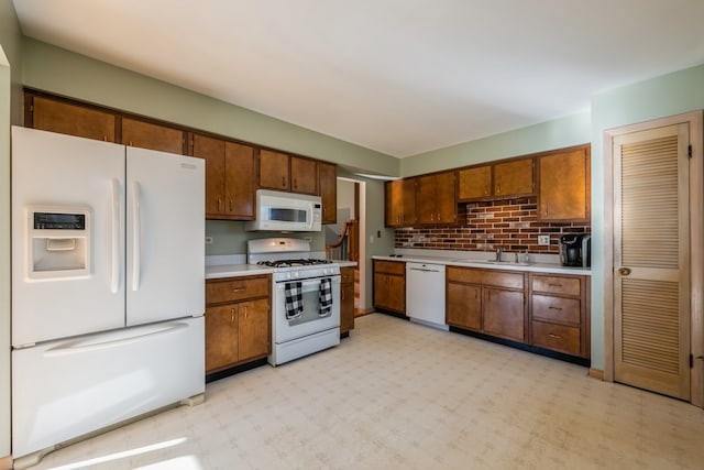 kitchen featuring decorative backsplash, white appliances, and sink