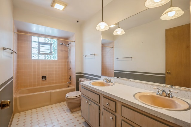 full bathroom featuring vanity, tiled shower / bath combo, and toilet