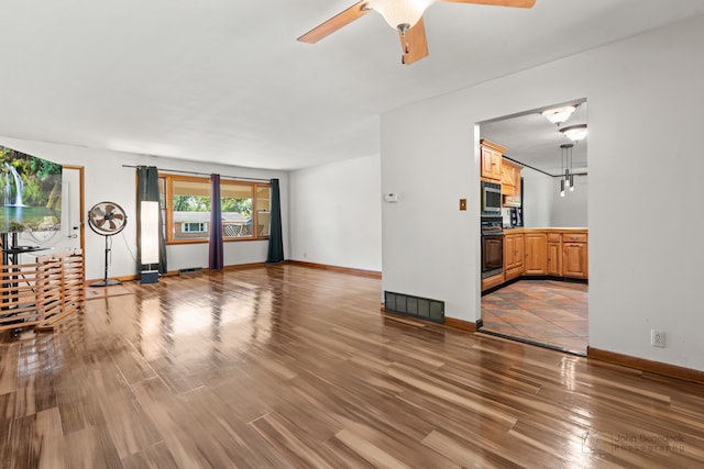 unfurnished living room featuring ceiling fan and wood-type flooring