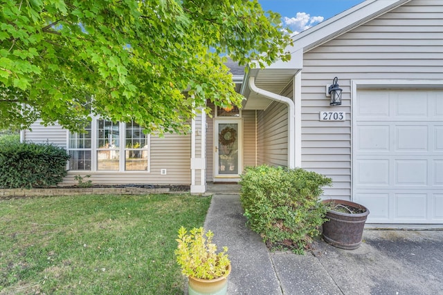 view of exterior entry featuring a garage and a lawn