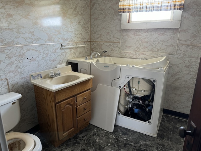 bathroom featuring vanity, toilet, and a washtub