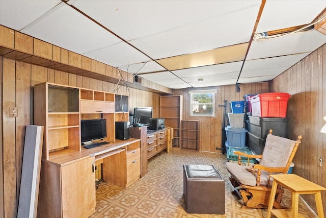 interior space featuring a drop ceiling, wooden walls, and built in desk