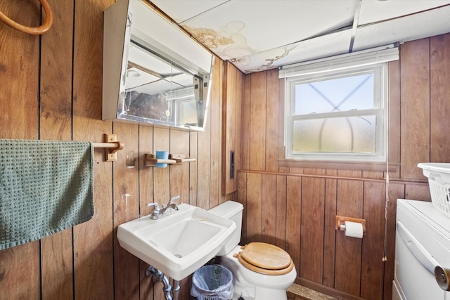 bathroom with sink, wooden walls, and toilet