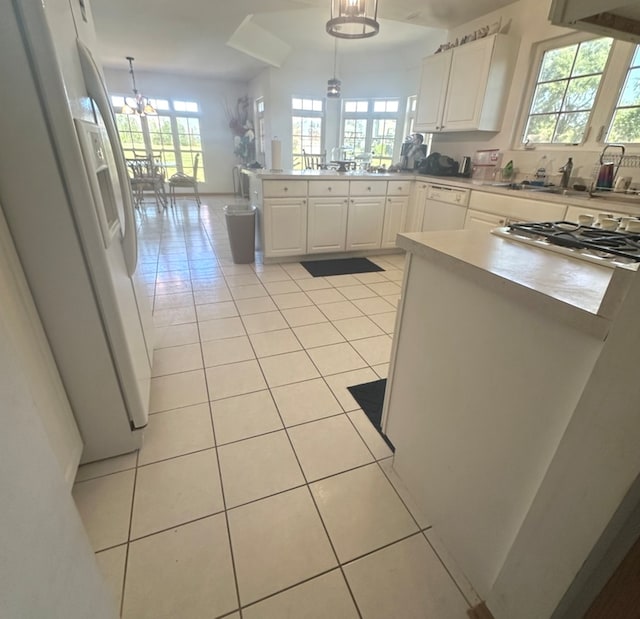 kitchen featuring white appliances, white cabinetry, light tile patterned floors, and decorative light fixtures