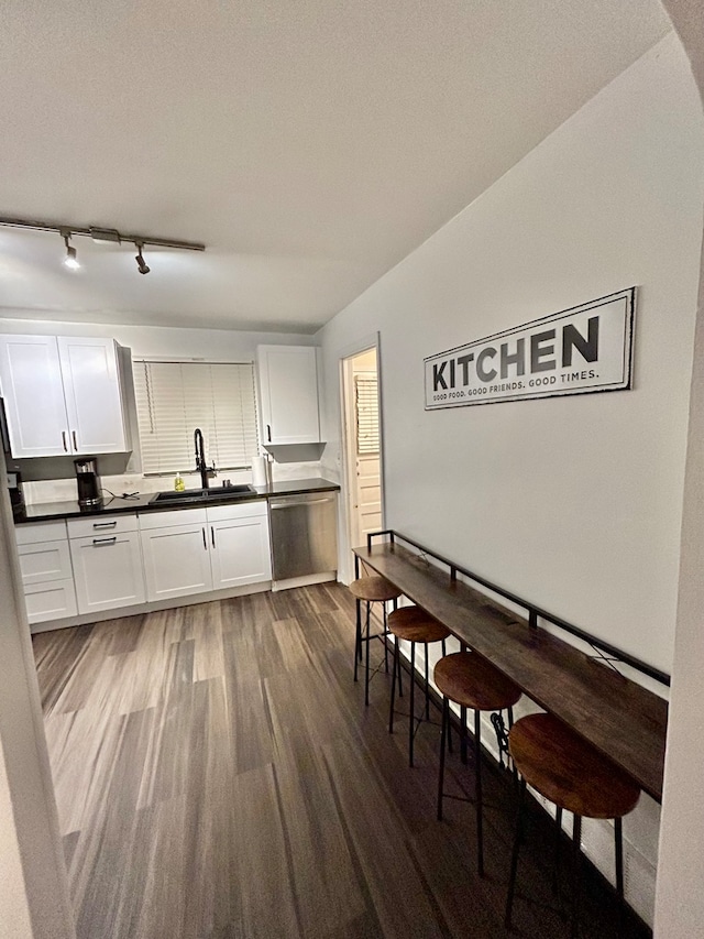 kitchen with stainless steel dishwasher, sink, dark wood-type flooring, and white cabinets