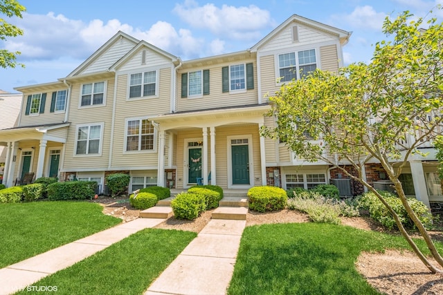 townhome / multi-family property with a porch, central AC unit, and a front yard